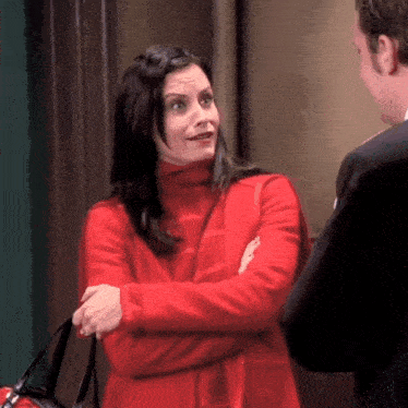 a woman in a red coat is standing next to a man