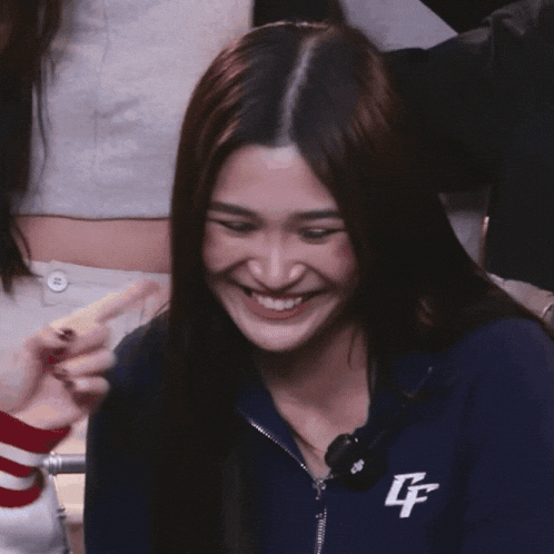 a woman wearing a blue jacket with the letter f on it smiles