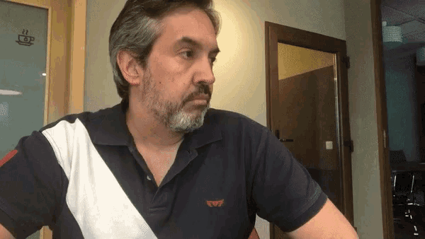a man with a beard is wearing a polo shirt with a wing logo on it