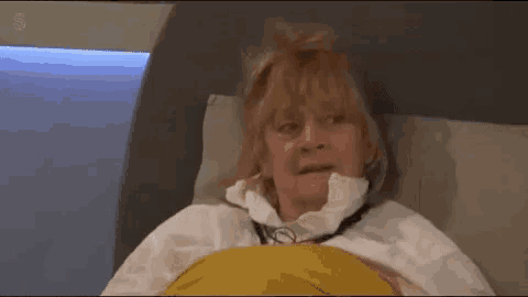 a woman is laying in a bed with a yellow blanket and a stethoscope around her neck .