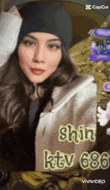 a woman wearing a beanie and a jacket is standing in front of a sign that says shin ktv 686