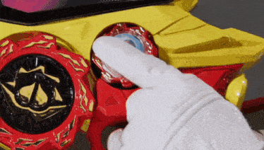 a person wearing a white glove is holding a red and yellow toy .