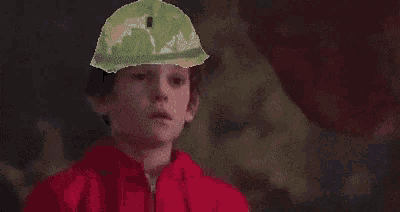 a man wearing a conical hat is talking to another man in a dark room .