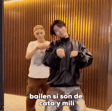 two men are dancing in front of a wall with the words bailen si son de cata y mili