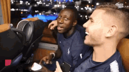 two men are sitting next to each other and one of them is giving a thumbs up sign