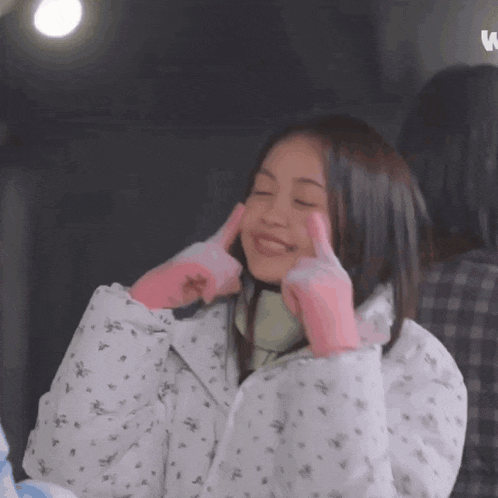 a woman wearing pink gloves is smiling and covering her ears