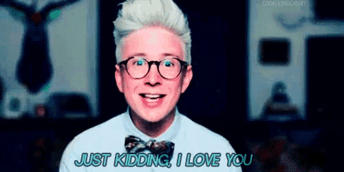 a man wearing glasses and a bow tie is smiling and saying just kidding i love you .