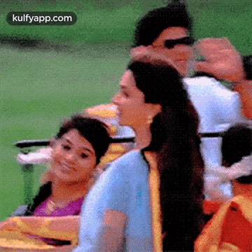 a group of people are sitting in chairs in a park and one of them is wearing sunglasses .