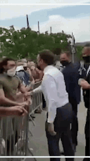a man in a white shirt is standing in front of a crowd .