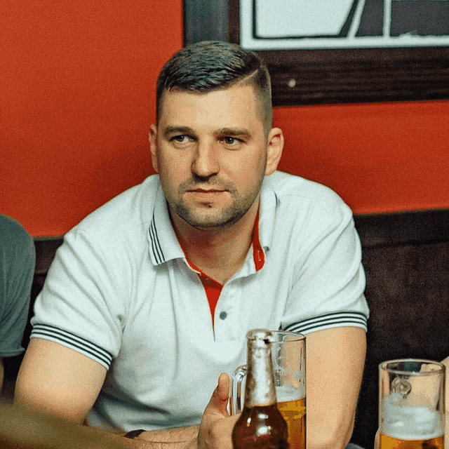a man sitting at a table holding a bottle of corona beer