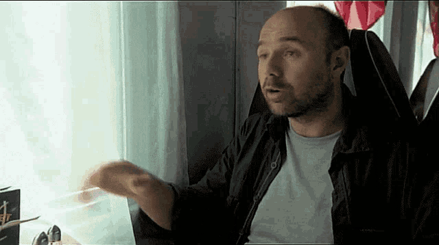 a man with a beard is sitting in front of a window