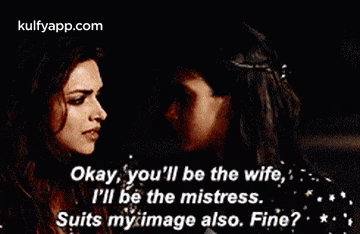 two women are standing next to each other and one of them is saying okay , you 'll be the wife .