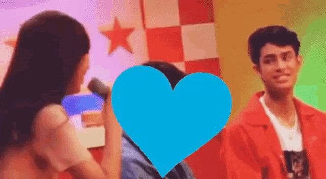 a woman holding a microphone with a blue heart in front of her