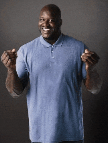 a man in a blue shirt is smiling and holding his hands up in the air