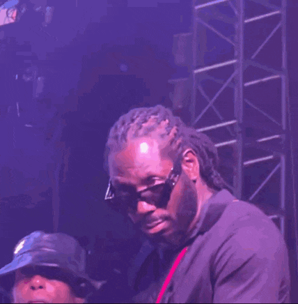 a man wearing sunglasses and dreadlocks is standing on a stage