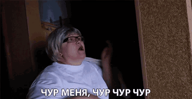 a woman wearing glasses and a wig is screaming in a dark room in russian