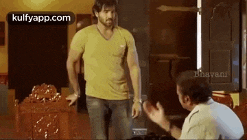two men are standing next to each other in a room and talking .