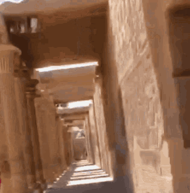 a very long hallway with columns and arches leading to a building