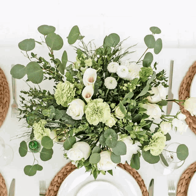 a bouquet of green and white flowers sits on a white table