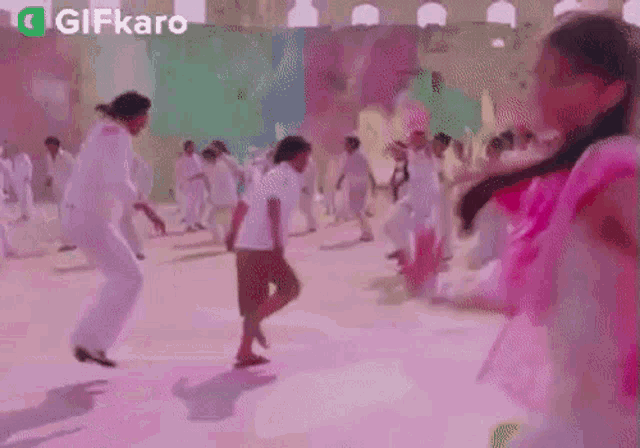 a group of people are dancing in a room with a pink wall in the background .