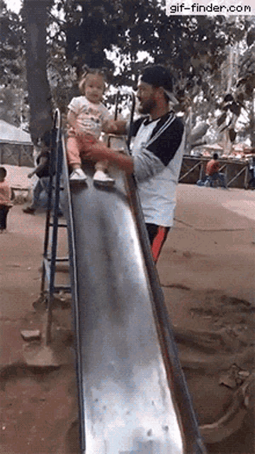 a man is holding a little girl on a slide and the website gif-finder.com is visible in the corner