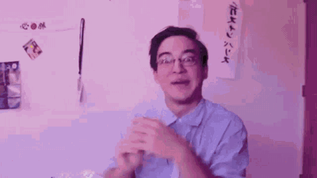 a man wearing glasses is clapping his hands in front of a wall that says oooooooh