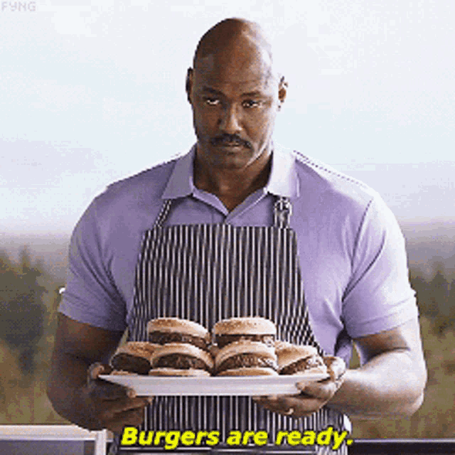 a man in an apron is holding a plate of hamburgers and says burgers are ready