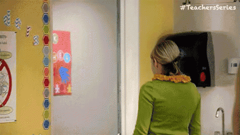 a woman in a green shirt is standing in front of a paper towel dispenser .