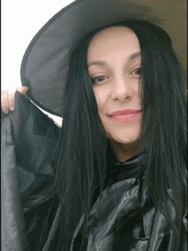 a woman with long black hair wearing a witch hat