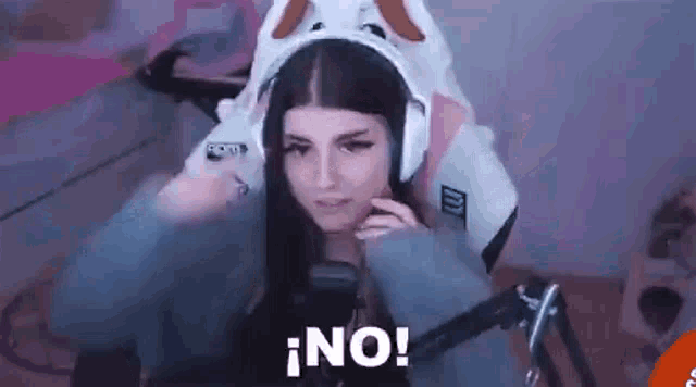 a woman wearing a bunny costume and headphones is sitting in front of a microphone and saying no .