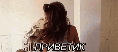 a woman is standing in front of a mirror with her hair blowing in the wind and the words `` приветик '' written in russian .