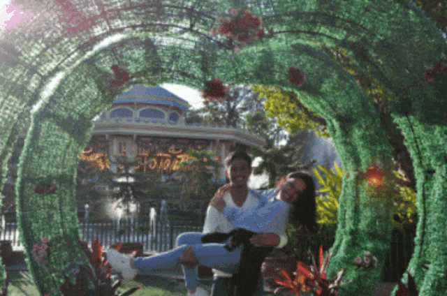 a man carrying a woman in his arms under a green archway