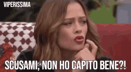 a woman is sitting in a chair with her hand on her chin and the words scusami non ho capito bene written above her .