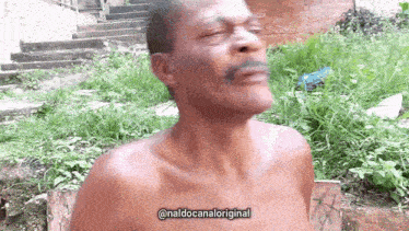 a shirtless man with a mustache is making a funny face in front of some grass and stairs .