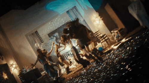 a group of women are dancing in a room with balloons and confetti on the floor