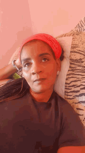 a woman wearing a red bandana is laying on a zebra print blanket
