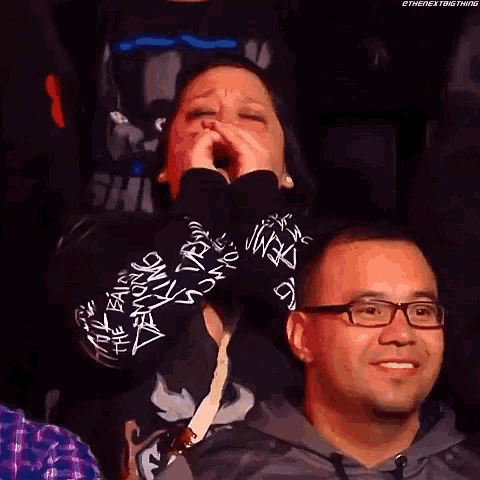 a man and a woman are sitting in a stadium and the woman is crying while the man is smiling .