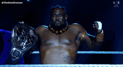 a man in a wrestling ring holding a belt that says ' the komdreesen ' on it