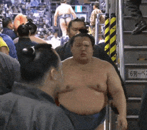 a sumo wrestler is walking down a set of stairs with a sign that says 6