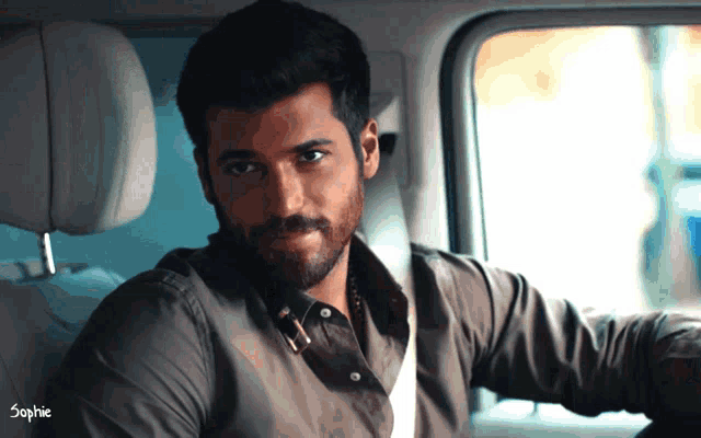 a man with a beard is sitting in the back seat of a car with the name sophie on the bottom