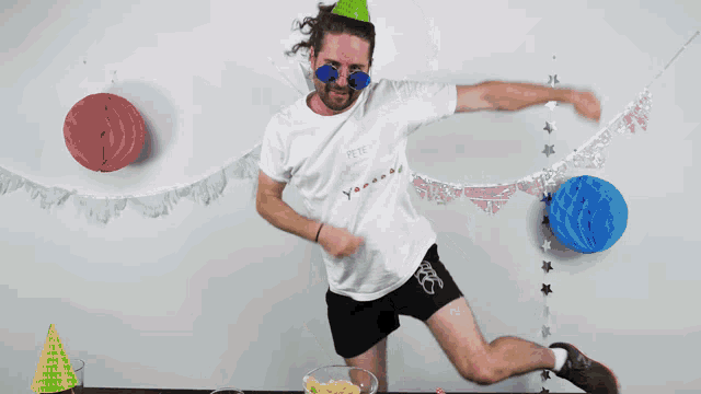 a man wearing a party hat and sunglasses holds a star in his hands