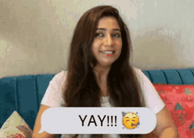 a woman is sitting on a couch with a speech bubble that says yay