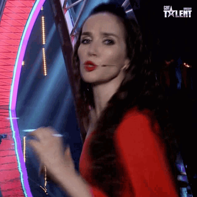 a woman in a red dress stands in front of a sign that says go talent