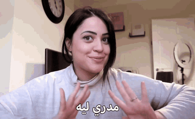 a woman wearing a white sweater with arabic writing on her face