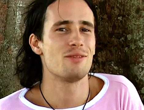 a close up of a man 's face with a pink shirt on