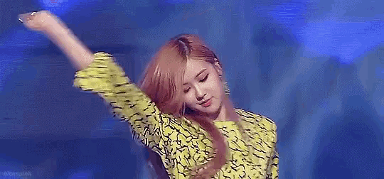 a woman in a yellow and black dress is dancing on a stage .