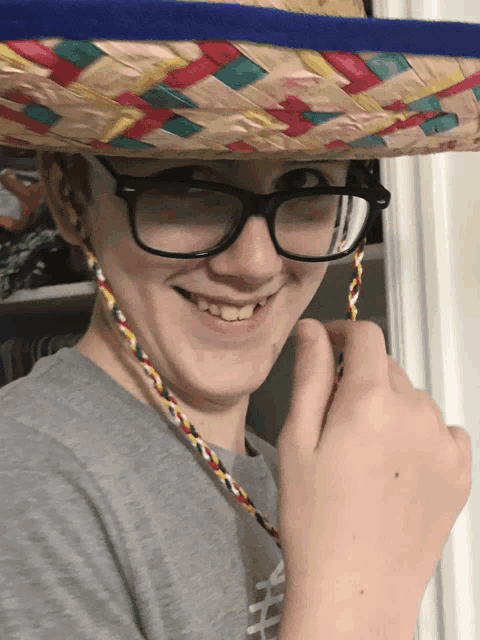 a young man wearing glasses and a sombrero smiles