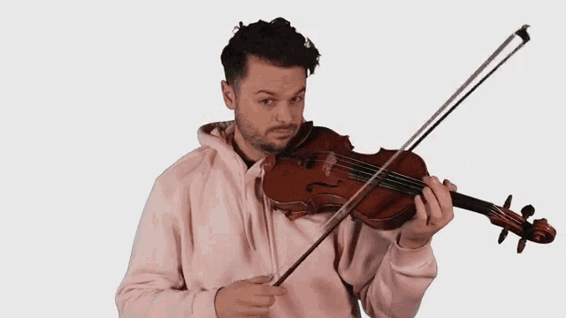 a man in a pink hoodie is playing the violin