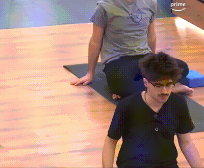 a man in a black shirt is sitting on a yoga mat next to another man in a grey shirt .