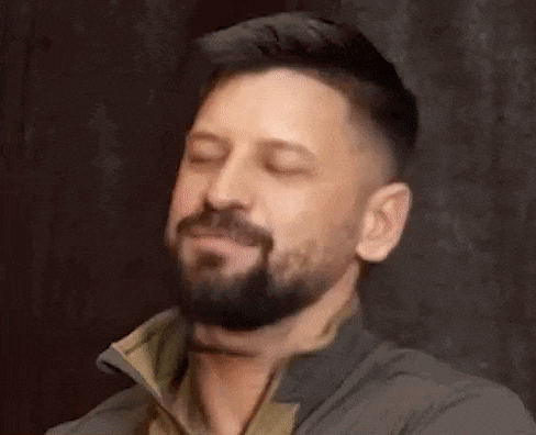 a man with a beard is smiling for the camera .